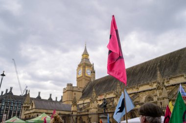 LONDON - 22 Nisan 2023: XR protesto yürüyüşüne katılın, parlamento yakınlarındaki protestocuların üzerinde yükselen bayrak, eylem ve dönüşüm ilhamı.