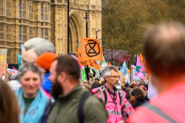 LONDON - 22 Nisan 2023: Protestocuların XR yürüyüşünde XR bayraklarını gururla göstererek Londra 'daki Parlamento Binası' nın önünde görsel bir gösteri yaratarak birlik deneyimi.