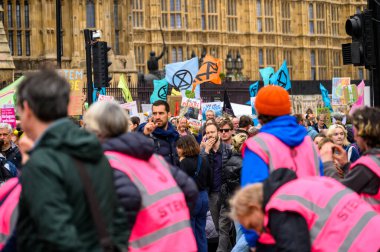 LONDON - 22 Nisan 2023: Parlamento binası önünde XR bayrakları taşıyan çok sayıda protestocunun güçlü sahnesi, Soykırım İsyanı yürüyüşünde çevresel adalet çağrısını güçlendiriyor