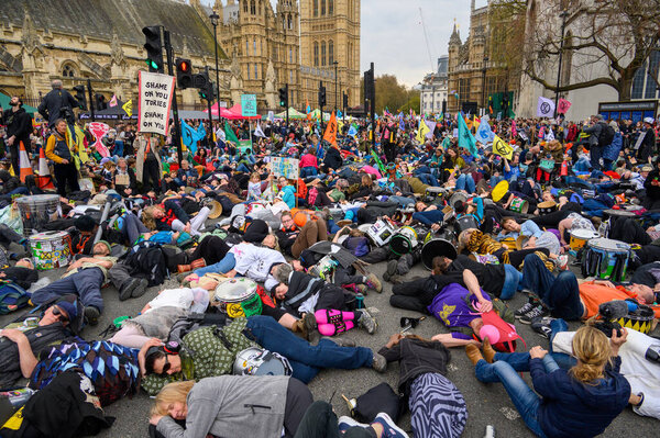 LONDON - April 22, 2023: Discover the emotional XR die-in protest as activists lie down before Parliament, conveying a solemn message about the climate crisis and the urgency for change.