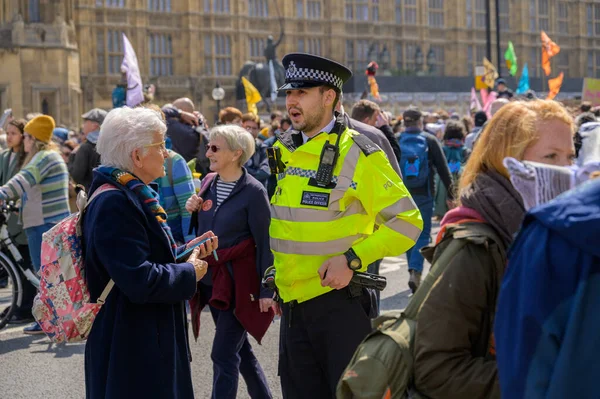 ロンドン 2023年4月22日 活動のなかでの人間関係 メトロポリタン警察官は ロンドンの議会の家の外で絶滅反乱デモで高齢女性と対話する ストック画像