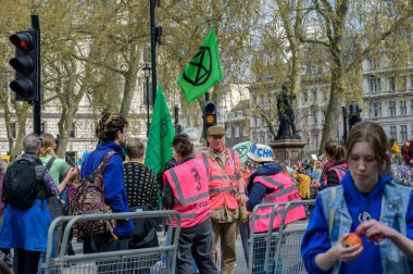LONDON - 22 Nisan 2023: Odak noktasında güvenlik: Yüksek görüşlü ceketli görevliler, Londra 'daki XR protesto yürüyüşüne nezaret ederek, herkes için güvenli bir ortam sağlandı.