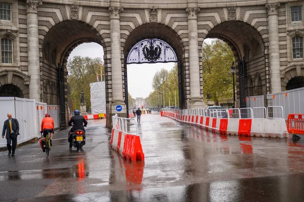 LONDON - 24 Nisan 2023: Kırmızı ve beyaz yol bariyerleri yağmurlu bir günde Buckingham Sarayı 'nın arka planında Amirallik Kemeri' ne giden yolu gösteriyor.