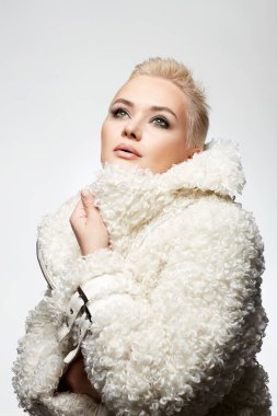young short blond hair woman in white fur. beautiful bald girl. Winter fashion