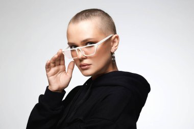 beautiful young woman wearing Hoodie and glasses. stylish bald girl with earrings