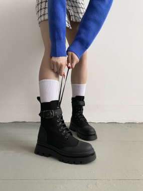 female legs in high black boots. fashionable young woman in stylish leather shoes and white socks