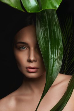 Palmiye yapraklı esmer kızın güzel portresi. Makyajlı güzel bir genç kadın. Doğal kozmetik konsepti