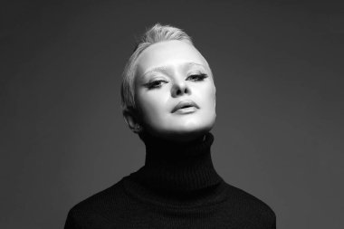 Kısa saçlı, beyaz kaşlı güzel bir kadının siyah beyaz portresi. Süslü makyajlı şehvetli sarışın kız. Kel stili