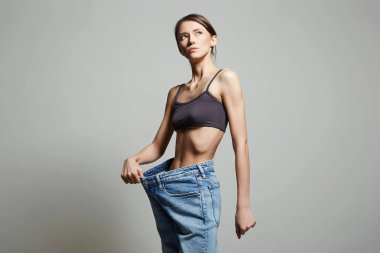 Kot pantolonlu genç kadını zayıflatıyor. Belden aşağısı. Güzel ince vücutlu kız. Stüdyo resmi