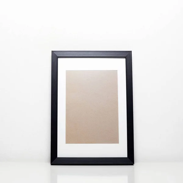 black picture frame on a table. Stylish photoframe with passe-partout for poster or pictute. Empty frames for mock up, with white passepartout, standing portait mode