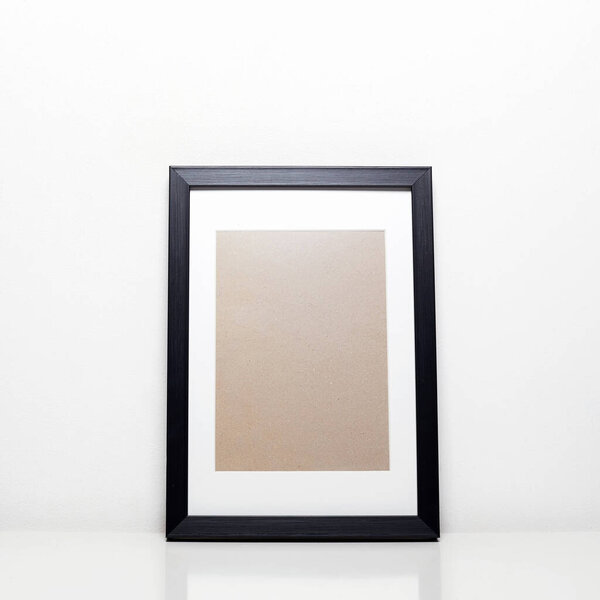black picture frame on a table. Stylish photoframe with passe-partout for poster or pictute. Empty frames for mock up, with white passepartout, standing portait mode