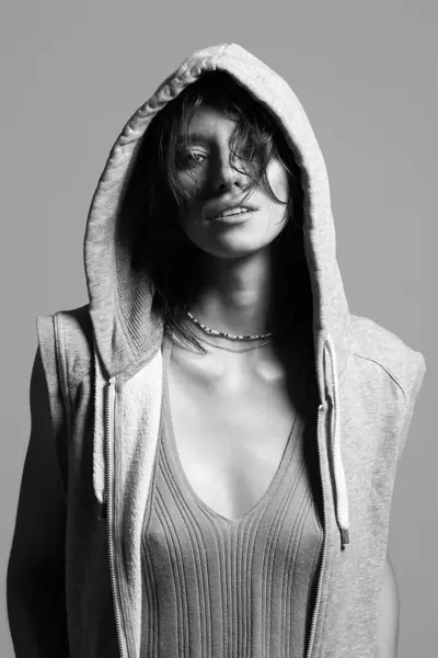 beautiful young woman in hood. sexy girl in grey hoodie. black and white portrait