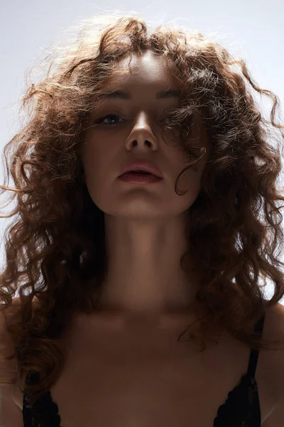 Kıvırcık saçlı güzel bir genç kadın. Güzel kız yüzünün yakın plan portresi.