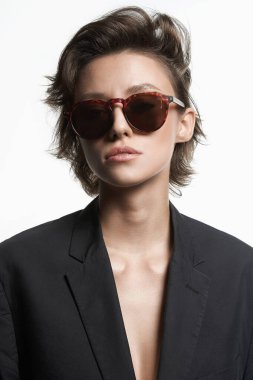 Güneş gözlüklü kısa saçlı güzel bir kadının moda portresi. Güzel seksi kız takım elbiseli ve gözlüklü beyaz tenli