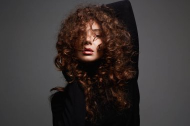 Kıvırcık saçlı güzel bir genç kadın. Sağlıklı saçlı kızın güzel portresi.