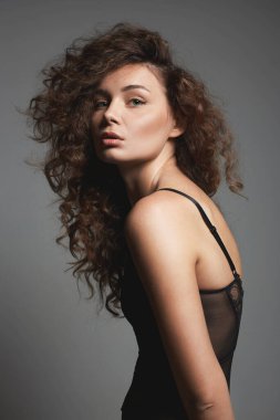 Kıvırcık saçlı güzel bir genç kadın. İç çamaşırlı güzel bir kızın güzel portresi.