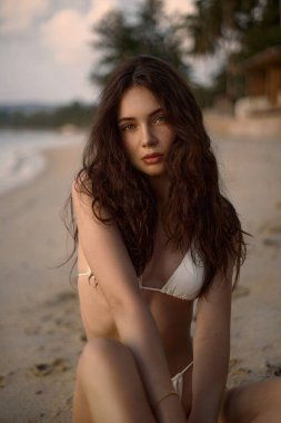 Sitting Beautiful model in sand on the beach. Sexy girl in Bikini. young brunette happy woman vacation in Thailand