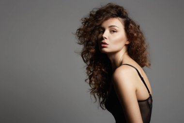 Kıvırcık saçlı güzel bir genç kadın. İç çamaşırlı güzel bir kızın güzel portresi.