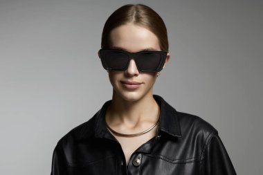 Beautiful young woman in sunglasses. blond girl in black glasses and leather coat