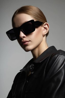 fashion portrait of Beautiful young woman in sunglasses. blond girl in black glasses and leather coat