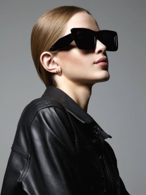 Beautiful young woman in sunglasses and leather coat. stylish blond girl in black glasses 