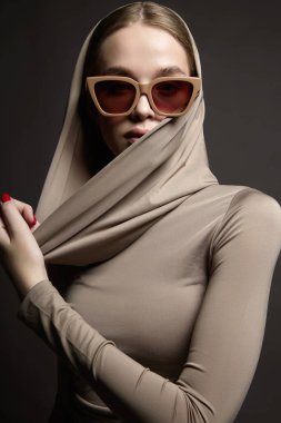 fashion portrait of Beautiful young woman in sunglasses and hood. beauty blond girl in trend glasses