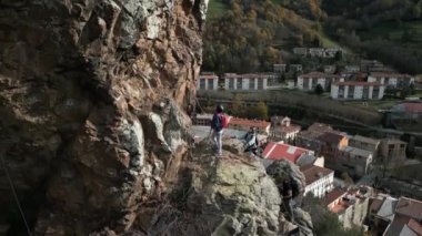 Uçuruma tırmanan dağcıların yavaş çekimleri, arkasında güzel bir kasaba, tepesinde de büyük bir haç, bir grup dağcının havadan insansız hava aracı görüntüsü, Katalonya 'da güzel bir arka planla uçuruma tırmanıyor.