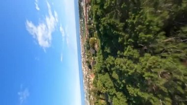 Dynamic vertical fpv view flying above trees in Premia de Dalt area, flying towards to the sea, low and close to green trees. 9 January 2023. High quality 4k footage