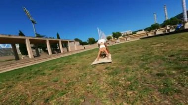 Dinamik fpv uzaktan kumandalı hava aracı beyaz elbiseli bir kızın etrafında uçarken güneşli bir günde çimlerin üzerinde egzersiz yaparken ve paspas kullanırken çekildi. Yüksek kalite 4k görüntü