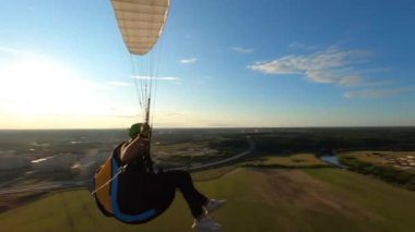 Güzel günbatımında tek başına uçan Paraglider, ormanın üzerinde uçan Fpv İHA 'sı başının üstünde uçuyor, ekstrem sporlar, yamaç paraşütü. Yüksek kalite 4k görüntü