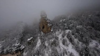 Doğal Sairme Sütunları 'nın FPV drone görüntüleri Georgia' daki karlı kayalara ve ağaçlara yakın bulutlarda uçuyor. Yüksek kalite 4k görüntü
