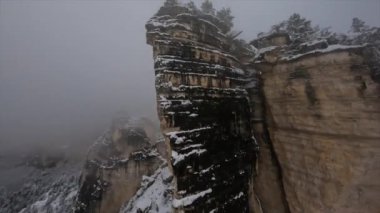Doğal Sairme Sütunları 'nın FPV drone görüntüleri Georgia' daki karlı kayalara ve ağaçlara yakın bulutlarda uçuyor. Yüksek kalite 4k görüntü
