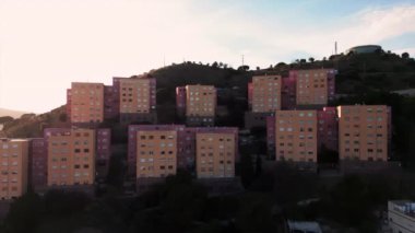 Santa Coloma bölgesinin havadan görünüşü, dağ yamacındaki konut binaları, parlak günbatımı. Katalonya, İspanya, Mart 2023
