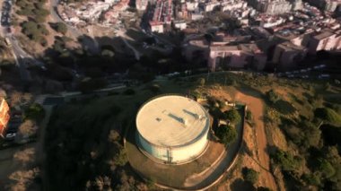 Barcelona 'da Santa Coloma de Gramenet bölgesinin beyaz, yuvarlak su rezervuarının hava manzarası, Parlak gün batımı, Katalonya, İspanya. Yüksek kalite 4k görüntü