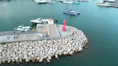 Cambrils Limanı 'ndaki deniz fenerinin yörüngesindeki hava manzarası, İspanya 2023' te kenetlenmiş yelkenli ve yatlar. Yüksek kalite 4k görüntü