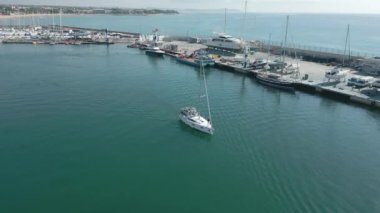 Yat limanından ayrılan küçük bir yelkenlinin havadan görünüşü. Yüksek kalite 4k görüntü
