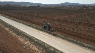Üzüm bağı kış manzarası. Traktör baharın başlangıcından önce toprağı işliyor. İspanya Yüksek Kaliteli 4k görüntü