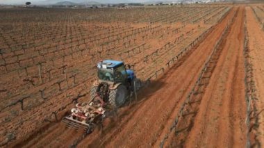 Üzüm bağı kış manzarası. Traktör baharın başlangıcından önce toprağı işliyor. İspanya Yüksek Kaliteli 4k görüntü
