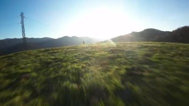 Gün batımında FPV İHA ile bacaklarının arasından alçak geçiş yüksek kaliteli 4K görüntü.