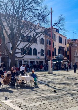 Venedik, İtalya - Nisan 2023. Güneşli bir günde Venedik sokaklarında yürüyen bir turist..