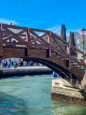 Venedik, İtalya - Nisan 2023. Yelkenli Venedik kanalları ve güneşli bir günde sokaklarda yürüyen turistler.