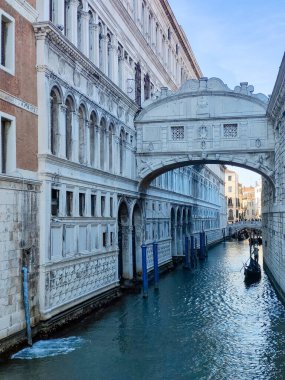 Venedik, İtalya - Nisan 2023. Yelkenli Venedik kanalları ve güneşli bir günde sokaklarda yürüyen turistler.