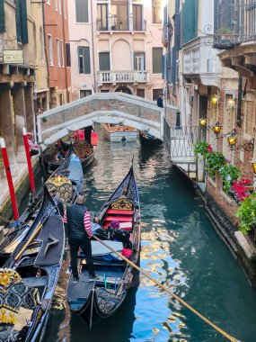 Venedik, İtalya - Nisan 2023. Yelkenli Venedik kanalları ve güneşli bir günde sokaklarda yürüyen turistler.