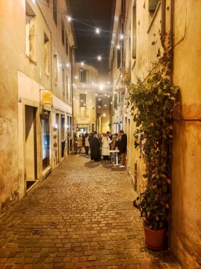 Bassano del Grappa, İtalya - Nisan 2023. Geceleyin İtalya 'nın kuzeyinde Bassano del Grappa sokaklarında turistler