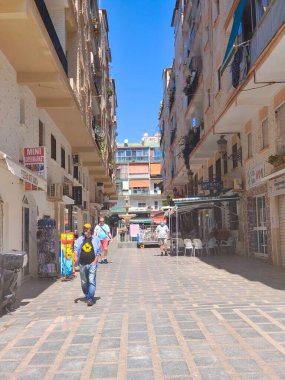 Torremolinos, İspanya - Mayıs 2022. İnsanlar yazın her iki tarafta da hediyelik eşya dükkanıyla sokakta yürüyorlar. İspanyol turistik kasabası..