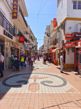 Torremolinos, İspanya - Mayıs 2022. İnsanlar yazın her iki tarafta da hediyelik eşya dükkanıyla sokakta yürüyorlar. İspanyol turistik kasabası..