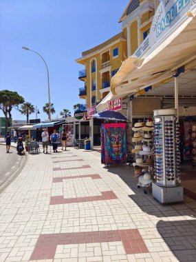 Torremolinos, İspanya - Mayıs 2022. İnsanlar yazın her iki tarafta da hediyelik eşya dükkanıyla sokakta yürüyorlar. İspanyol turistik kasabası..