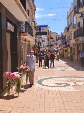 Torremolinos, İspanya - Mayıs 2022. İnsanlar yaz aylarında sokakta kahve dükkanının yanında yürürler. İspanyol turistik kasabası..