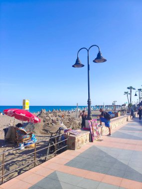 Torremolinos, İspanya - Mayıs 2022. İnsanlar yazın öğleden sonra bir tarafında kahve dükkanıyla sokakta yürüyorlar. İspanyol turistik kasabası..