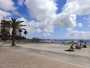 San Javier, Murcia, İspanya - 10 Haziran 2022. La Manga del Mar Menor sahilinde palmiye ağaçlı turistler. Akdeniz 'de güneşli bir gün..
